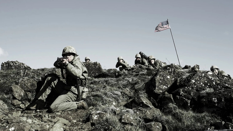 Soliders at the Battle of Iwo Jima, firing their weapons, an American Flag in the background