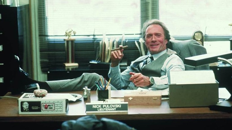 Clint Eastwood, feet kicked up on an office desk, enjoying a cigar