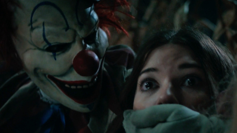 Friendo with his hand over a girl's mouth in Clown in a Cornfield