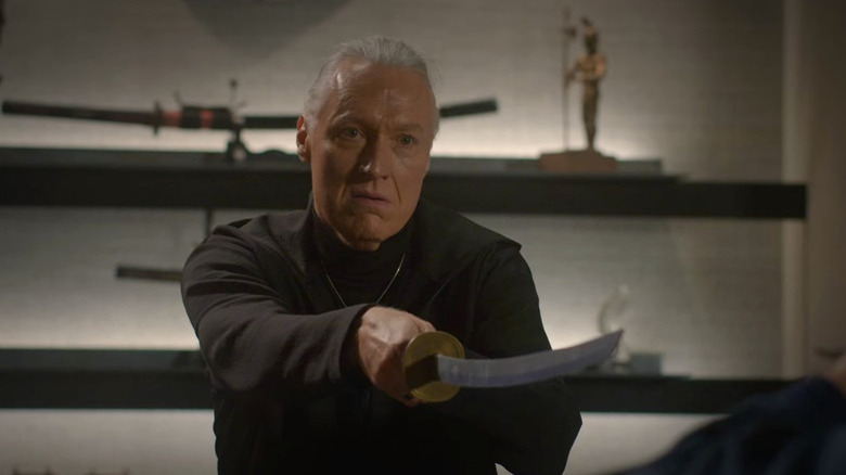 Terry Silver aponta uma katana para uma vítima invisível em Cobra Kai