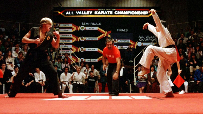 Johnny Lawrence stands in front of Daniel LaRusso who is in a crane kick stance in The Karate Kid