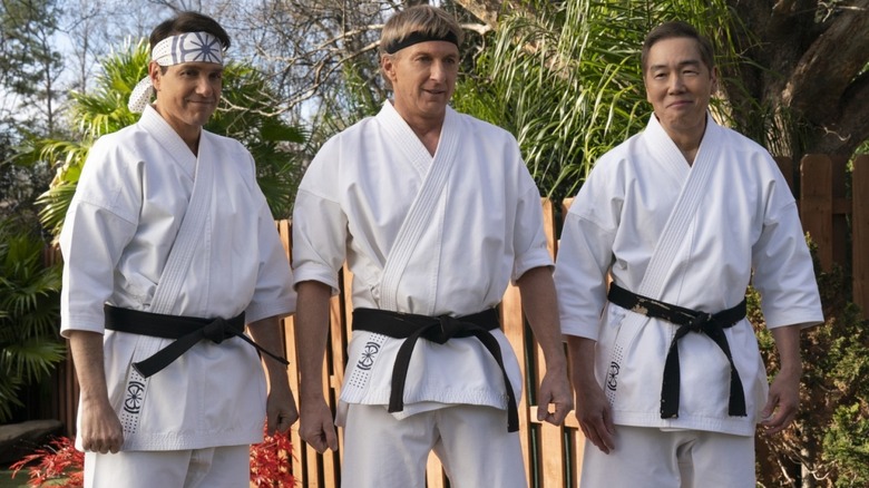 Ralph Macchio's Daniel LaRusso, William Zabka's Johnny Lawrence, and Yuji Okumoto's Chozen Toguchi side by side on Cobra Kai