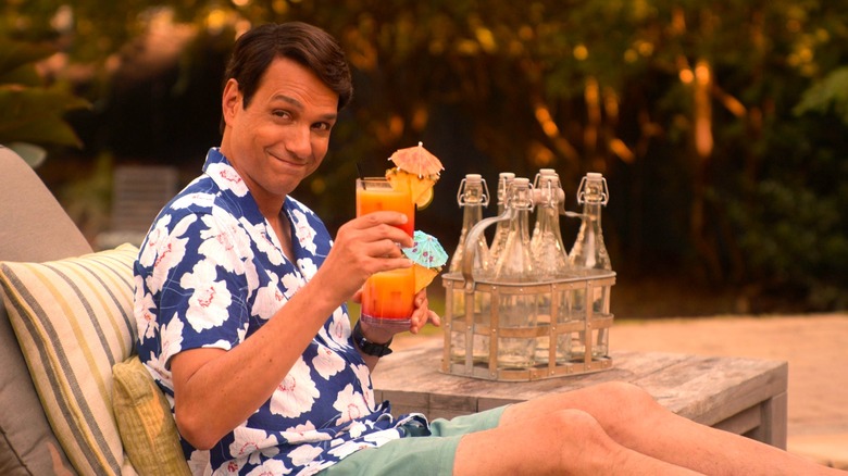 Daniel LaRusso lounging by the pool and lifting a cocktail in salute