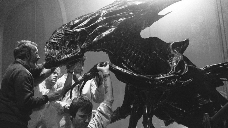 Behind the scenes photo of Stan Winston (left) and fx crewmembers working on an alien queen puppet for Aliens (1986)