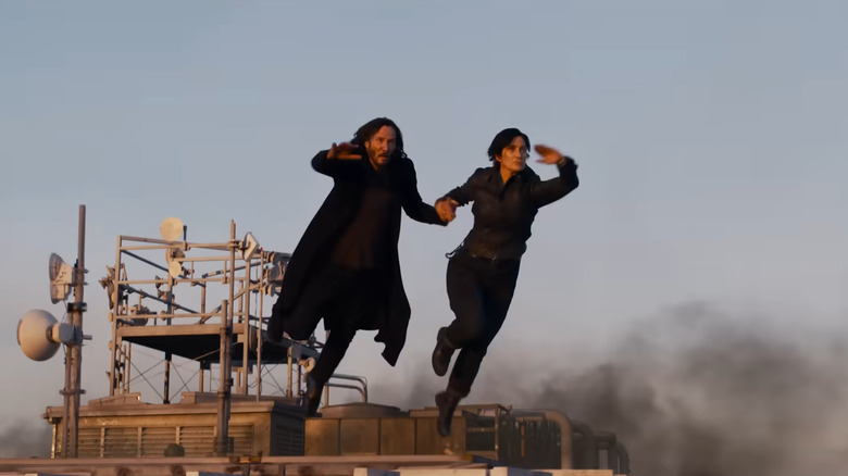 Keanu Reeves and Carrie-Anne Moss jumping through the air