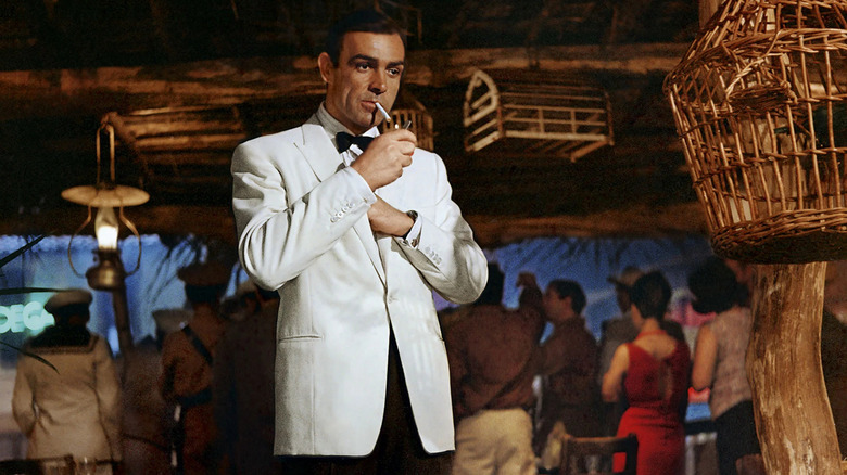 Sean Connery's James Bond lighting up a cigarette in his white suit in Goldfinger