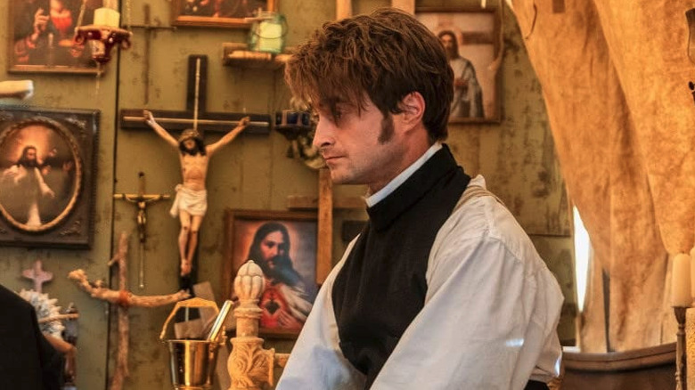 Daniel Radcliffe as Reverend Ezekiel sitting on his bed