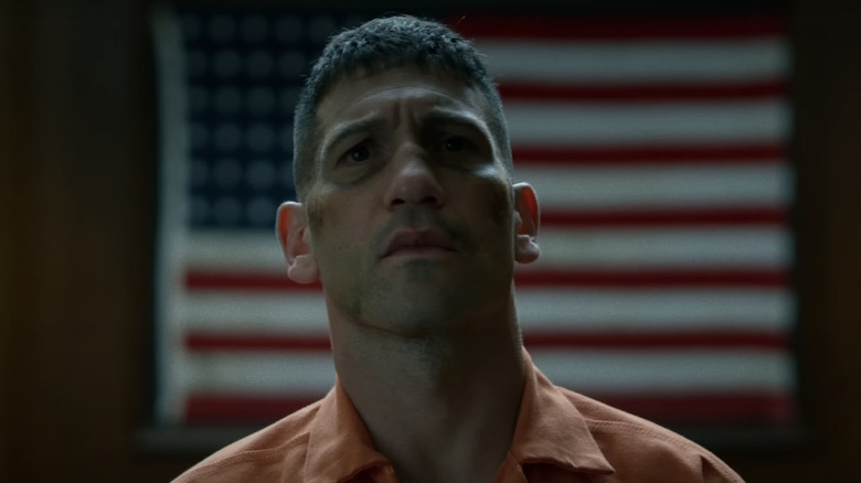 Jon Bernthal's Frank Castle stands in a jump suit in front of the US flag in The Punisher