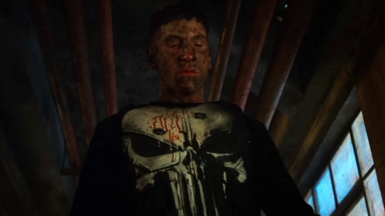 Jon Bernthal's Frank Castle stands looking down while covered in blood in The Punisher