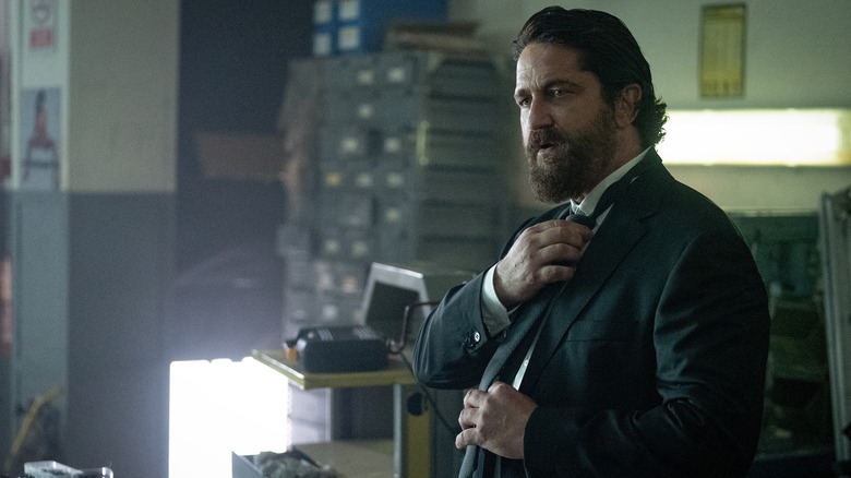 Big Nick straightens his tie while wearing a suit in Den of Thieves 2: Pantera