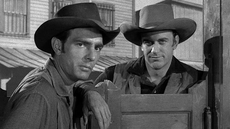 Dennis Weaver as Chester Goode stands at the entrance to a saloon next to James Arness as Matt Dillon in Gunsmoke