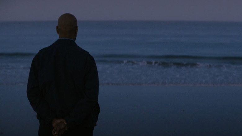 Denzel Washington's Robert McCall stands on the shoreline looking out to sea at sunrise in The Equalizer