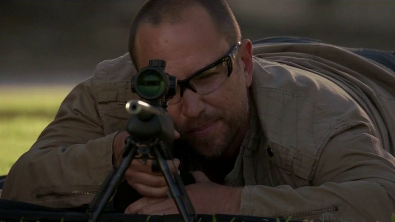 Karl Herlinger as Oleg Mickic laying on his stomach and aiming a sniper rifle on Dexter