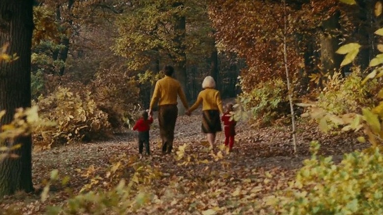 Francois, Emilie, and Francois' children walk in a park holding hands