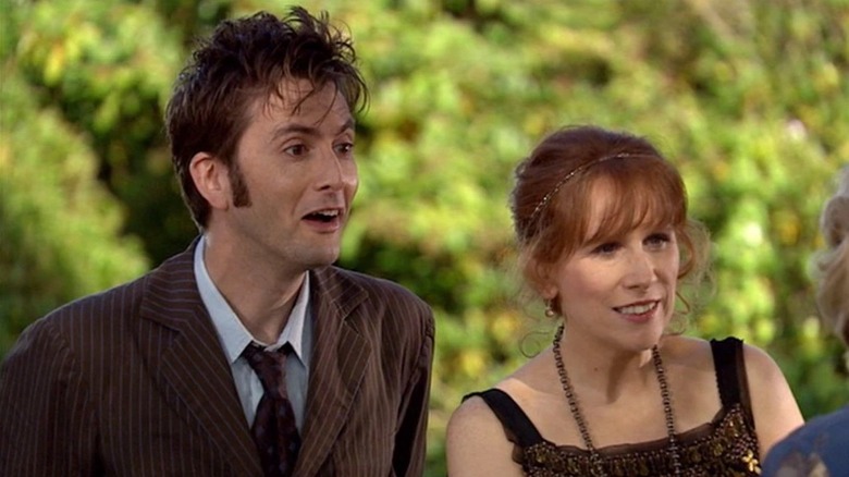 The Doctor (David Tennant) and Donna Noble (Catherine Tate) smile at someone offscreen in Doctor Who