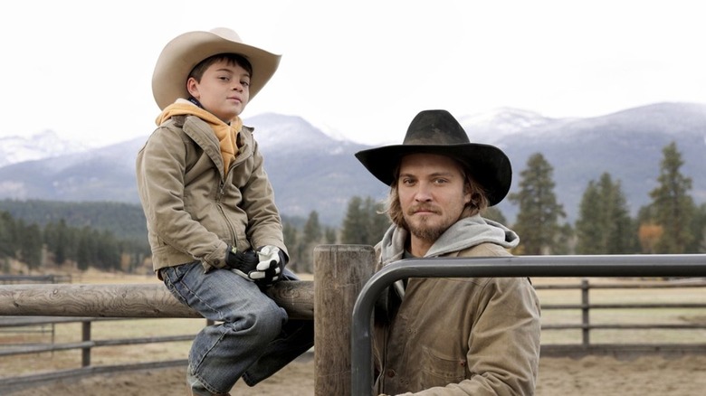 Tate sitting on a fence next to Kayce Dutton in Yellowstone