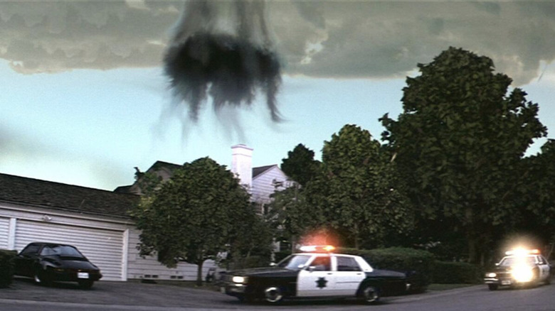 The portal opens up above the Darko family's white suburban home as police vehicles with flashing lights park in front of the house