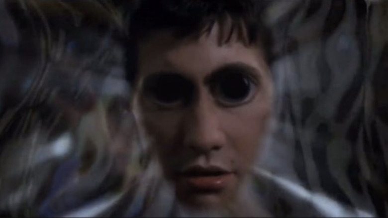 Jake Gyllenhaal's distorted face with oversized eyes in Donnie Darko as he looks into a portal