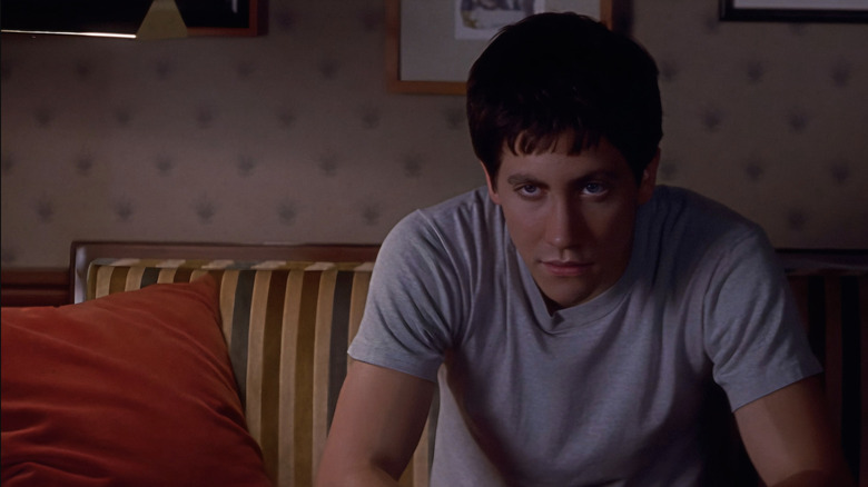 Jake Gyllenhaal as Donnie Darko in a gray t-shirt sitting in the therapist's office and looking extremely tired