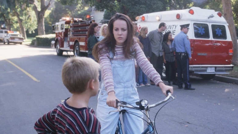 Jena Malone as Gretchen in Donnie Darko on a bicycle talking to a small boy in front of firetrucks