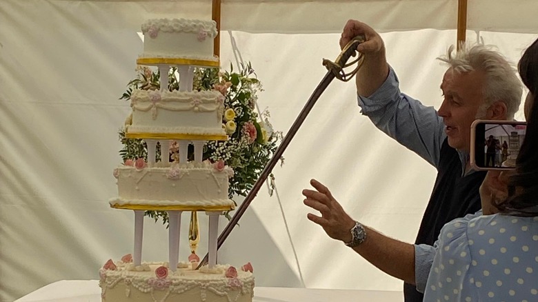 Owner of Belchamp Hall cutting into a wedding cake with an antique sword