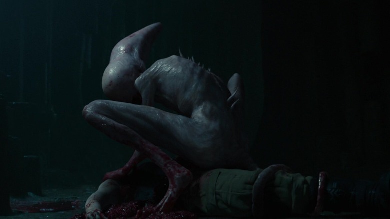 Neomorph from Alien: Covenant crouching over eviscerated body