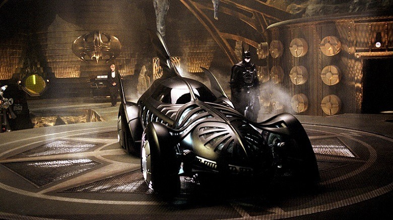 Batman standing beside his fancy new Batmobile