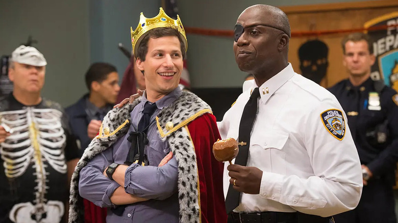 Jake Peralta in crown and Captain Raymond Holt smile in Brooklyn Nine-Nine