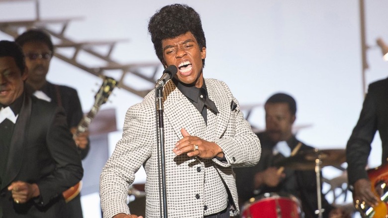 Chadwick Boseman as James Brown, singing with a band in Get On Up