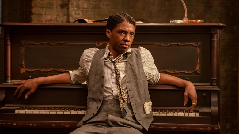 Chadwick Boseman as Levee Green leans against piano in Ma Rainey's Black Bottom