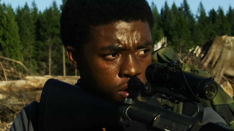 Chadwick Boseman as Samuel Drake, carrying an assault rifle in The Kill Hole