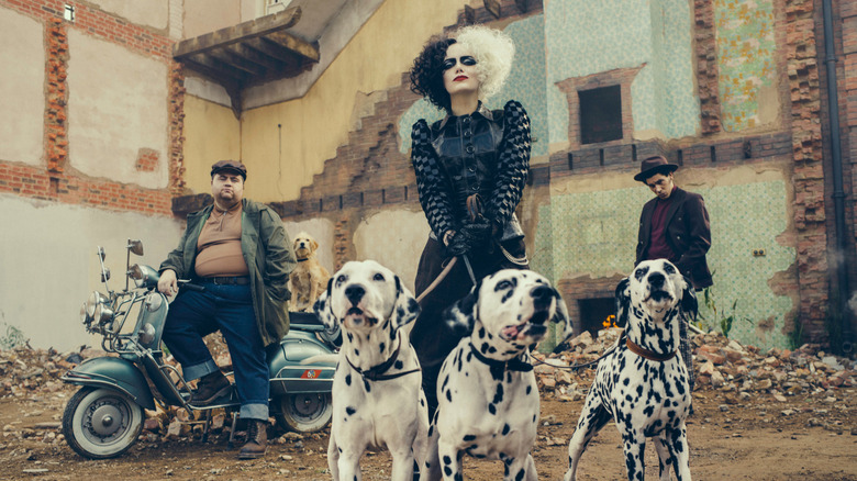 Cruella (Emma Stone) poses with three dalmatians in Cruella