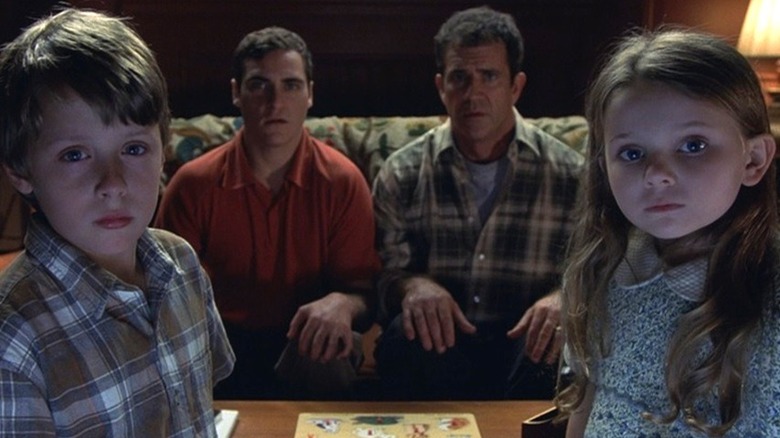 Rory Culkin, Joaquin Phoenix, Mel Gibson, and Abigail Breslin sit on couch in Signs