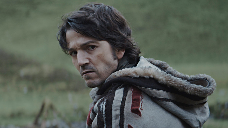 Diego Luna scowling gray coat