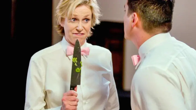 Constance looks at Ron intensely, holding up a kitchen knife covered in pieces of pepper