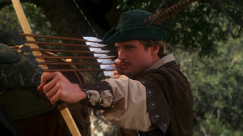 Cary Elwes aiming a shotgun arrow