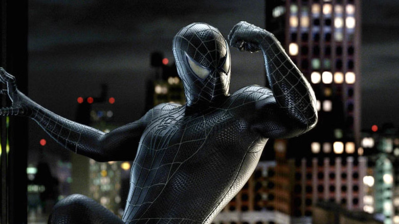 The symbiote suit Spider-Man flexes his arm while hanging on the side of a skyscraper in Spider-Man 3