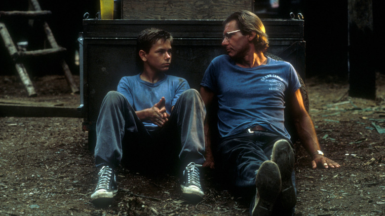 Allie (Harrison Ford) and Charlie (River Phoenix) sitting on ground in The Mosquito Coast