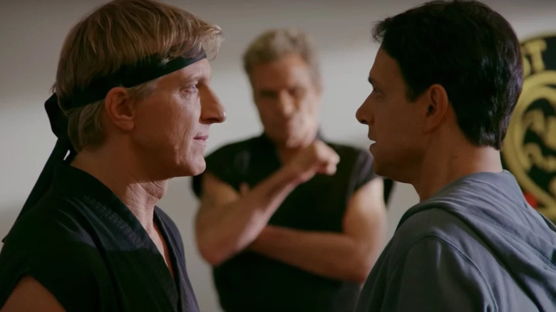 Johnny and Daniel face each other while Kreese watches in the background in Cobra Kai