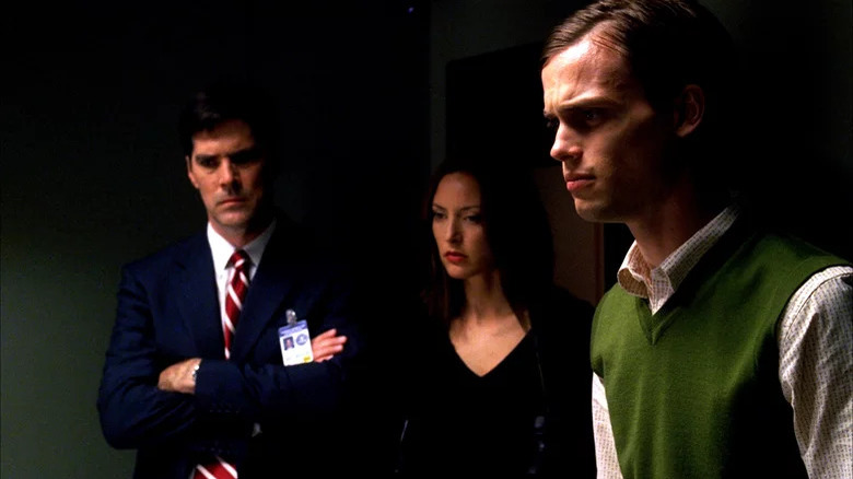 Criminal Minds' Hotch, Elle, and Reid standing in dark room