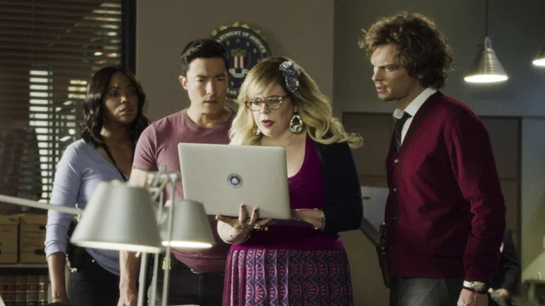 Criminal Minds' Garcia holding laptop by Lewis, Simmons, and Reid