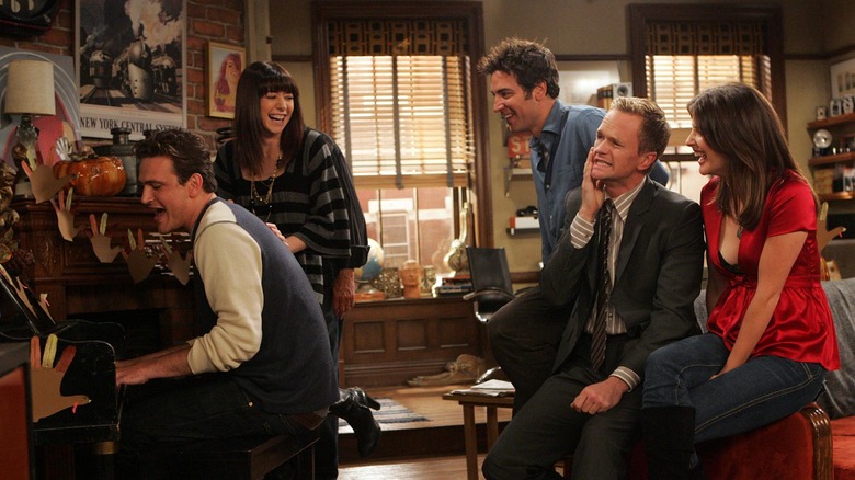 Marshall playing the piano while Barney soothes his face and Lily, Ted, and Robin laugh on How I Met Your Mother