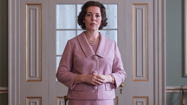 Olivia Colman's Queen Elizabeth II stands alone in a pink suit in The Crown