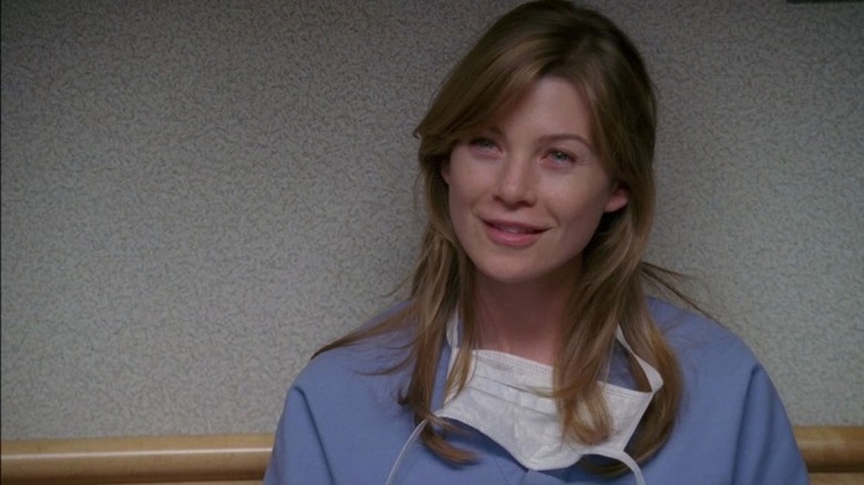 A young Meredith Grey smiling in hospital scrubs in Grey's Anatomy
