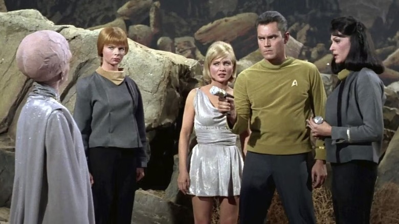 Pike (Jeffrey Hunter) aims a phaser at a Talosian while surrounded by women in Star Trek: The Original Series