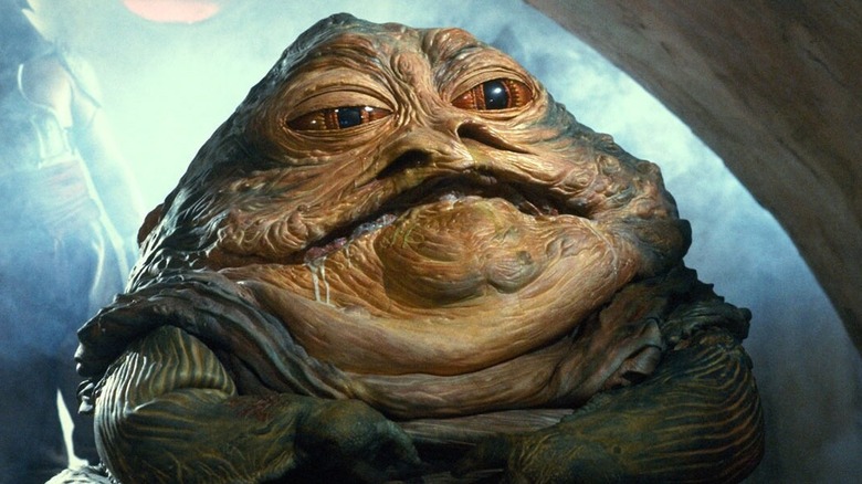 Jabba the Hutt sitting on his throne in his palace in Star Wars: Return of the Jedi