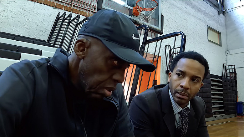 Bill Duke and André Holland sit at basketball court