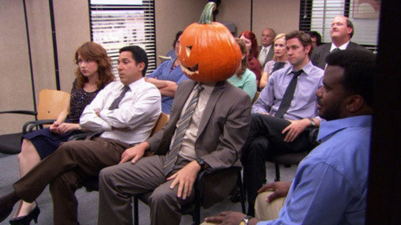 Dwight sits in a meeting with a pumpkin head