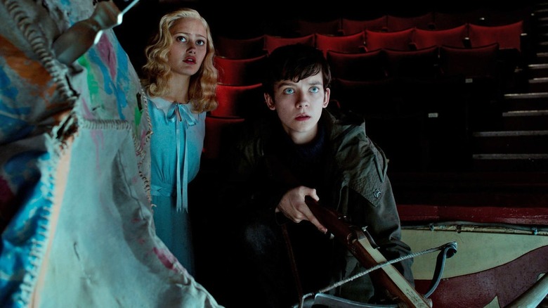 Asa Butterfield looking concerned and holding a crossbow