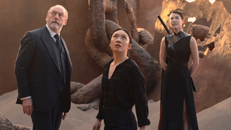 Liam Cunningham as Wade, Jess Hong as Jin Cheng, Sea Shimooka as Sophon look to the sky while standing in a desert in 3 Body Problem